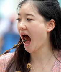Duan Ying, 24, samples fried scorpion in Wangfujing, Beijing. WANG JING / CHINA DAILY - F201305170813397337247902