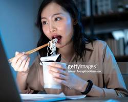 Image of college student eating ramen with chopsticks