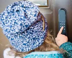 person installing a smart door lock with a keypad and fingerprint scanner.の画像