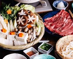 Image of Shabu shabu hot pot with thinly sliced meat, vegetables, and dipping sauces