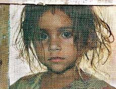 Three-year-old Indian refugee Ashu Sharma looks through a netted door at a migration camp in Samba sector, some 40 km from Jammu, on Wednesday. - ind7