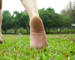 Person Running Barefoot Through Grass