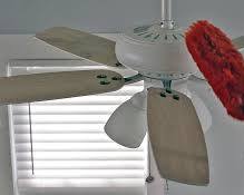 Image of person reaching up to clean a ceiling fan with a microfiber cloth