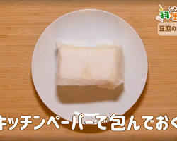 豆腐をキッチンペーパーで包み、重石を乗せて水切りするの画像